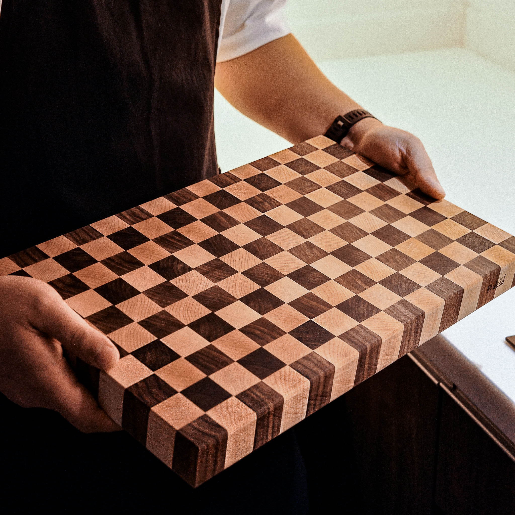 Person holding a wooden checkered cutting board